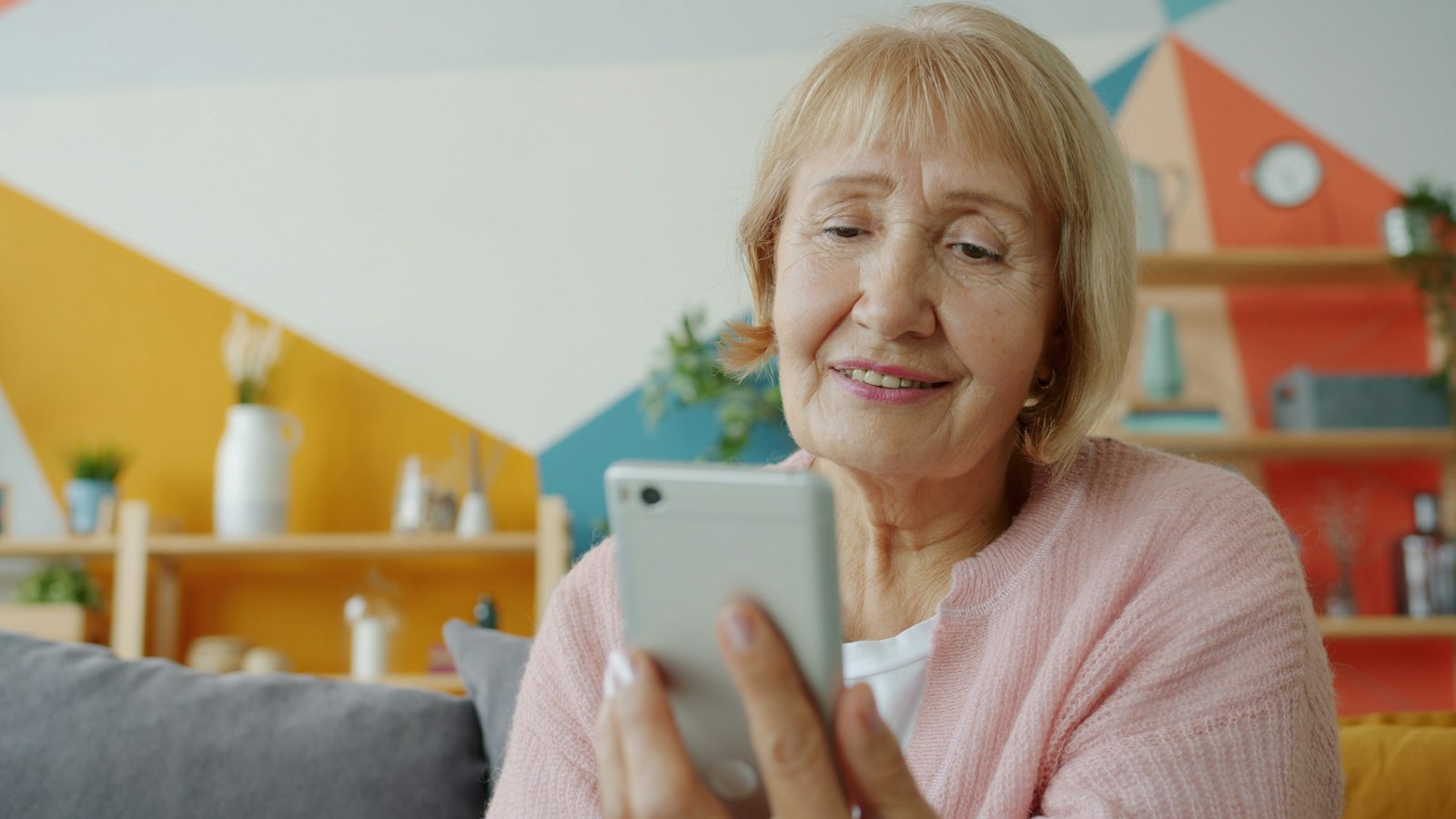 Aposentada sorri ao conferir no celular a data do pagamento do INSS de outubro